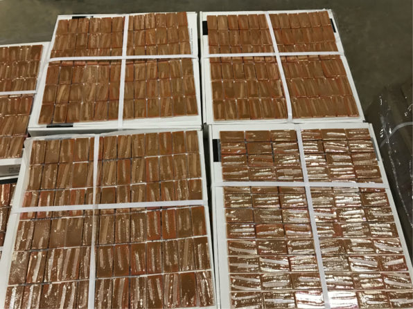 Photo of a pallet of small glass mosaic tile, in an iridescent copper color.